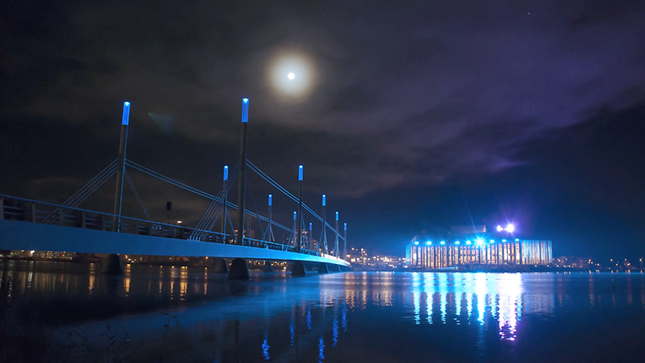 Bron över munksjön med Kulturhuset Spira i bakgrunden, fotat på kvällen med ett blått ljus över hela bilden