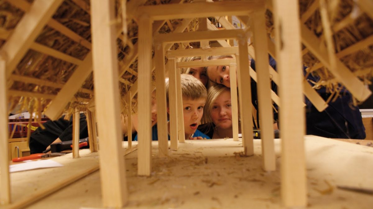 Barn tittar in i en liten träbyggnad