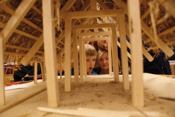 Barn tittar in i en liten träbyggnad