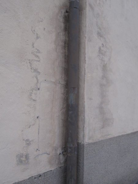 En sådan här skada på fasaden härrör nästan alltid från stupröret. Även om väggen för närvarande är torr, syns tydliga spå efter vattenskada.