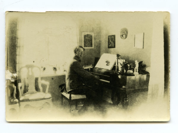 John Bauer sittandes framför ett piano
