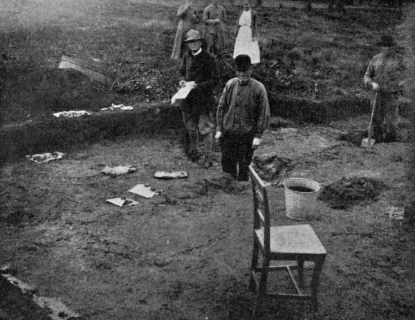 Undersökning från 1918. Flera personer arbetar i grävandet. En stol står vid kanten.