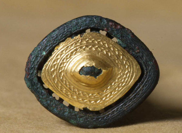 Ett guldbleck på undersidan av ett svärdshandtag.