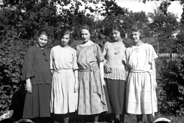 Fem unga kvinnor i en trädgård