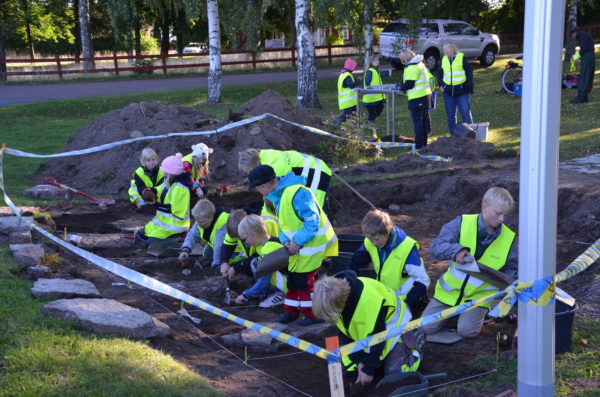 Unga barn från klass 3-6 arbetar som arkeologer och gräver.