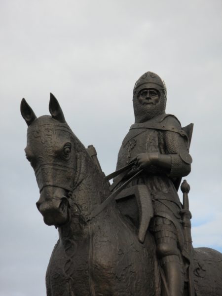 En staty med en person i rustning, hjälm och svärd sitter på en häst som även den är utrustad.