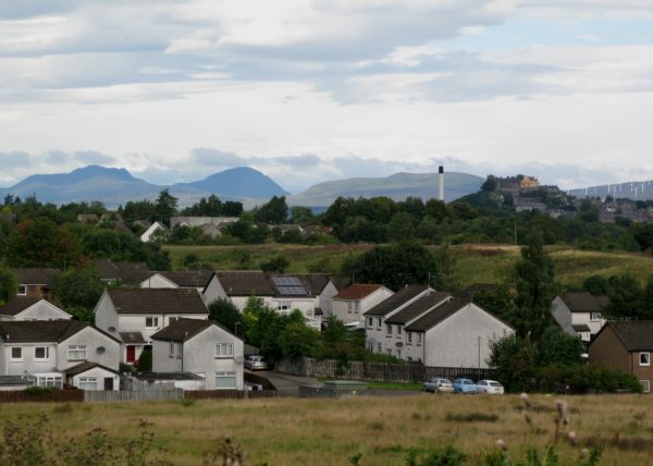 Bild över bostadsområde där Stirling Castle syns på sin klippa i bakgrunden. Bredvid finns en modern skorsten.