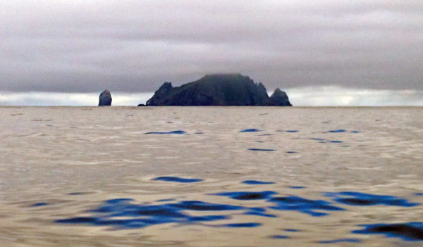 En ö med höga kanter och ett fågelberg bredvid stiger över havet.