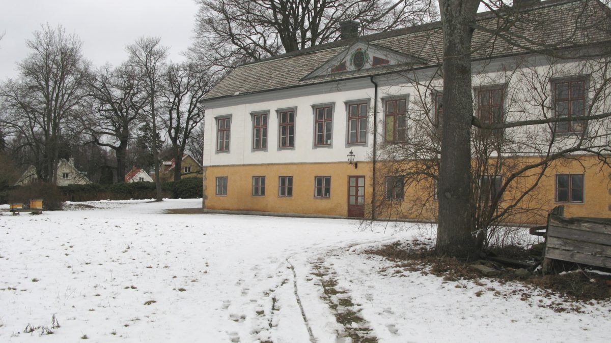 Bild över Rosenlunds herrgård. Snö på marken och stora gamla träd här och där omkring herrgården.