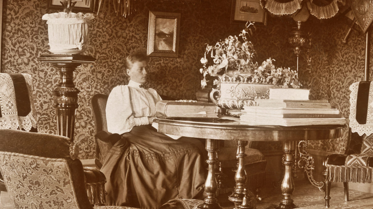 Hanna Friberg i sitt hem vid ett bord fullt av album och bokverk