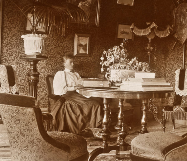 Hanna Friberg i sitt hem vid ett bord fullt av album och bokverk