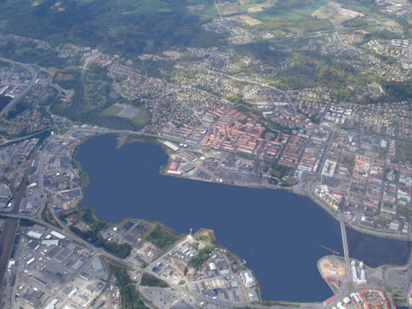 Flygbild över en stad. På bildens syns en stor sjö, hus och vägar.
