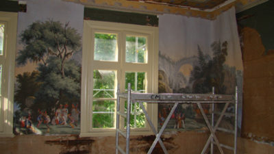 Målningar av konstverk hänger på väggarna. Mitt i rummet står en byggnadsställning.
