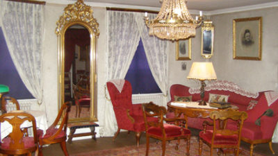 Rum med röda möbler, kristallkrona som taklampa och spegel med guldram.