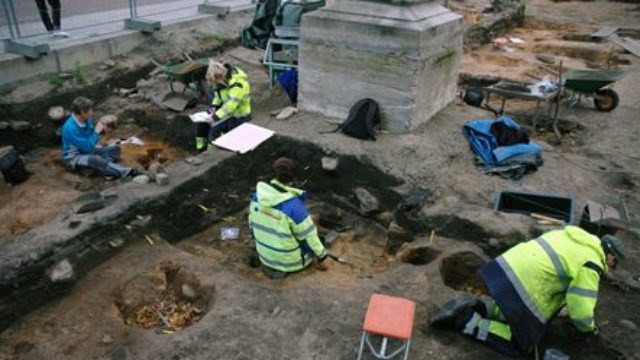 Fyra arkeologer undersöker ett område.