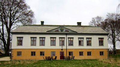 Bild på Rosenlunds herrgårdspark. En gul och vit byggnad.