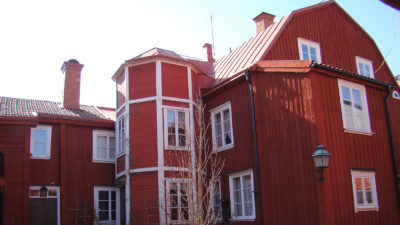 Röd träbyggnad med vita knutar och fönsterkarmar.