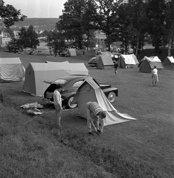 Campingplats. Två personer sätter upp ett tält.