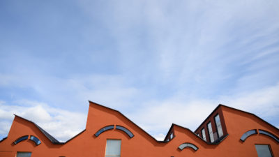 Museibyggnadens vågiga arkitektur i terracotta, mot en blå himmel med lätta moln