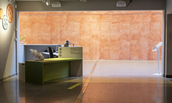 En grå informationsdisk till vänster och en orange stenvägg i bakgrunden