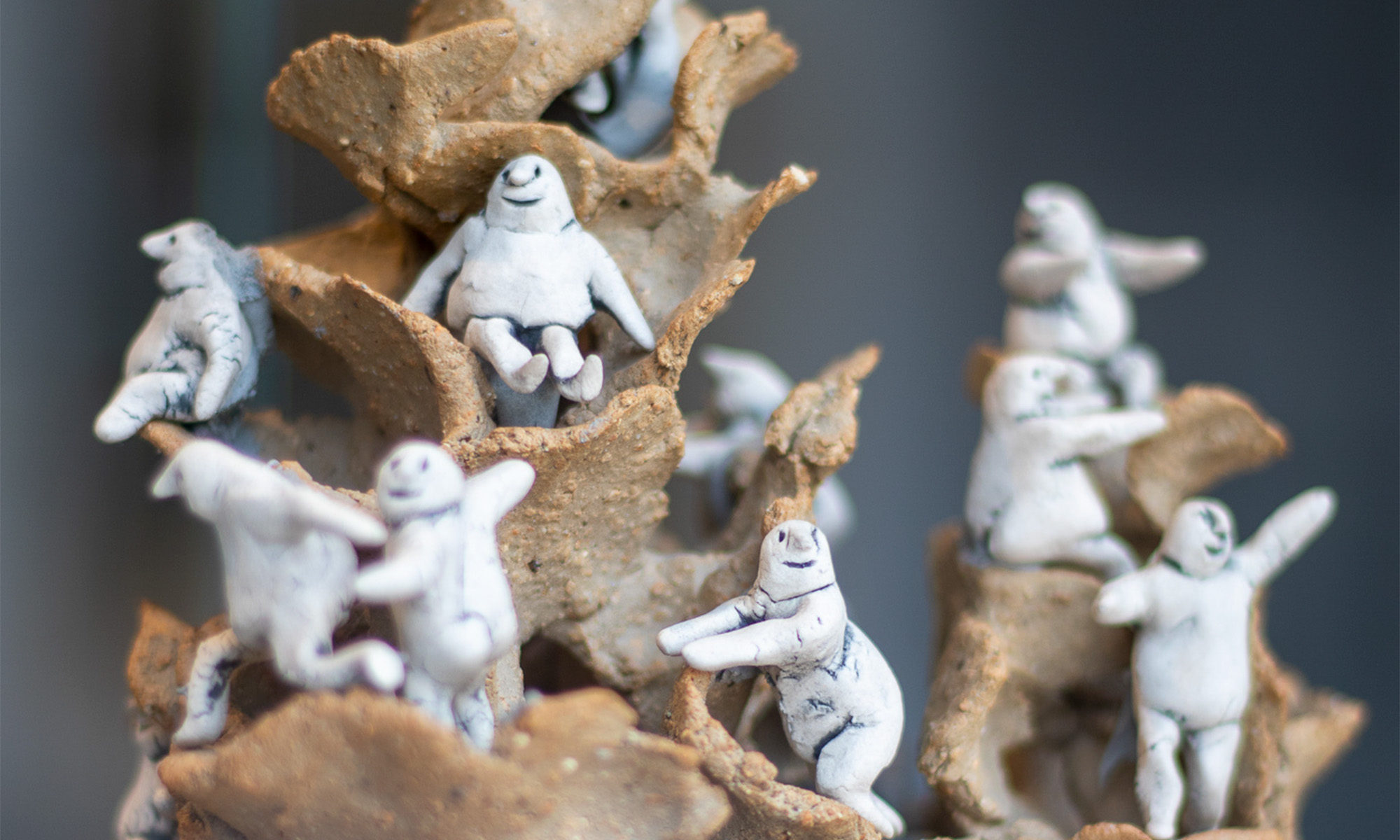 Konstverk med vita glada gubbar som klättrar på bruna högar