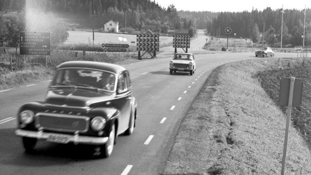 Svartvitt arkivfoto med bilar i äldre modell körandes på en landsväg