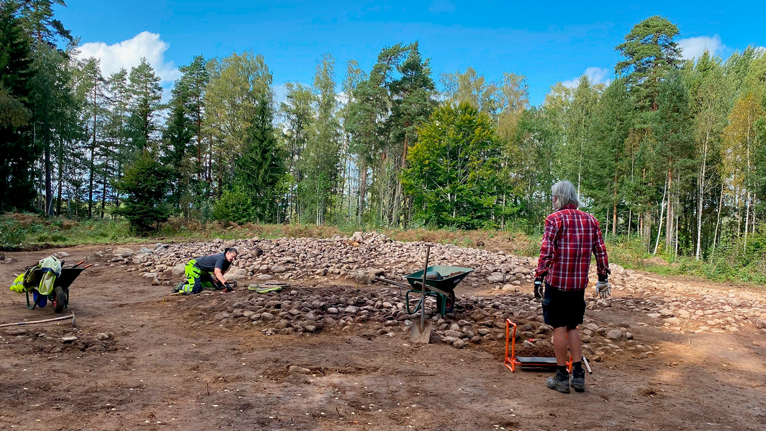 Två arkeologer arbetar vid ett gravfält en sensommardag
