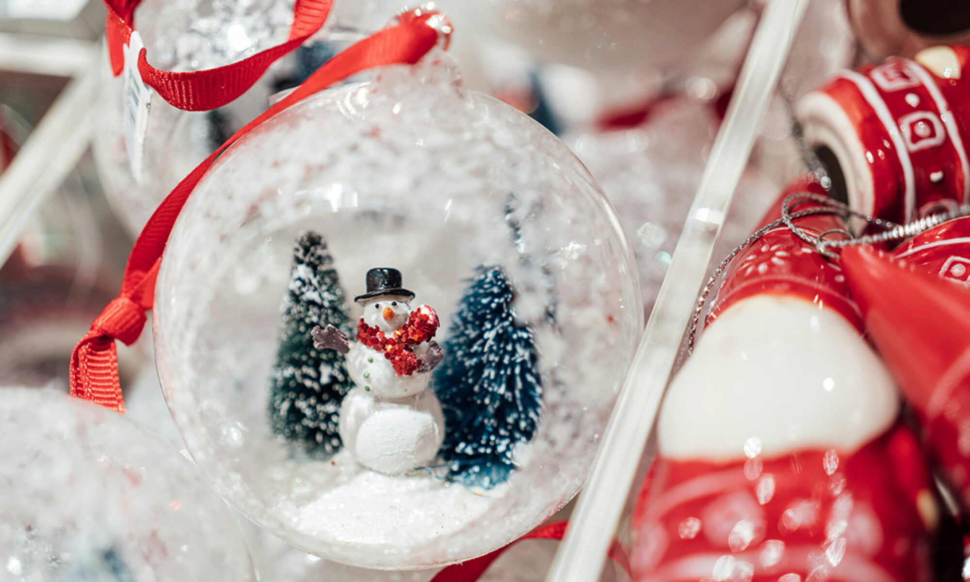 Snögubbe inuti en glaskula omgiven av julsaker