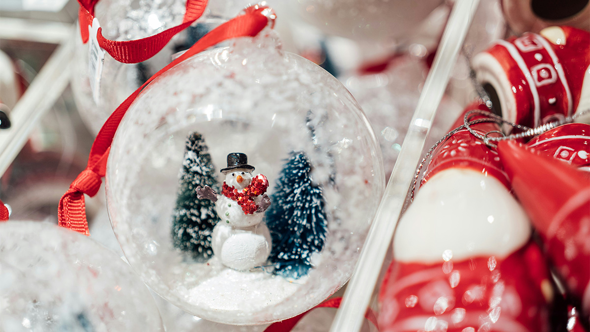 Snögubbe inuti en glaskula omgiven av julsaker