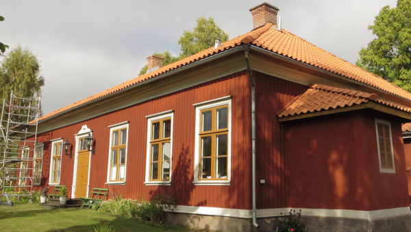 En rödmålad byggnad med gulorange fönsterfoder och dörr