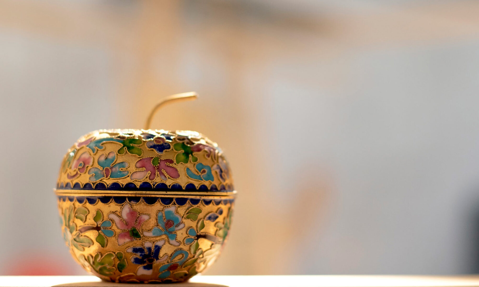 Guldigt äpple med mönster står på en bänk.