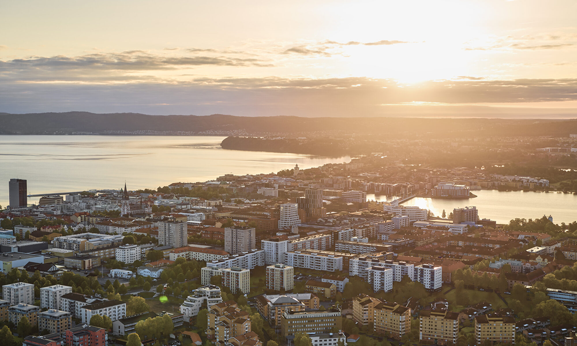 Morgonljus över en stad, där man ser två sjöar