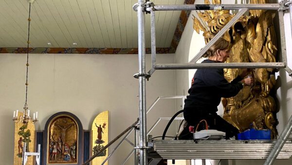 Konservator arbetar med ett förgyllt huvudbanér i Grevbäcks kyrka.