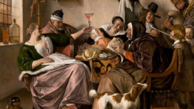 Män och kvinnor i 1600-talskläder sitter runt ett bord och dricker.